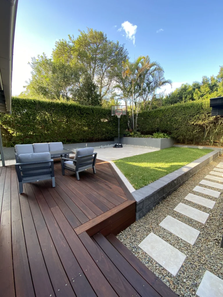 NF Build landscaped backyard with timber deck, outdoor seating, lawn, and paver pathway