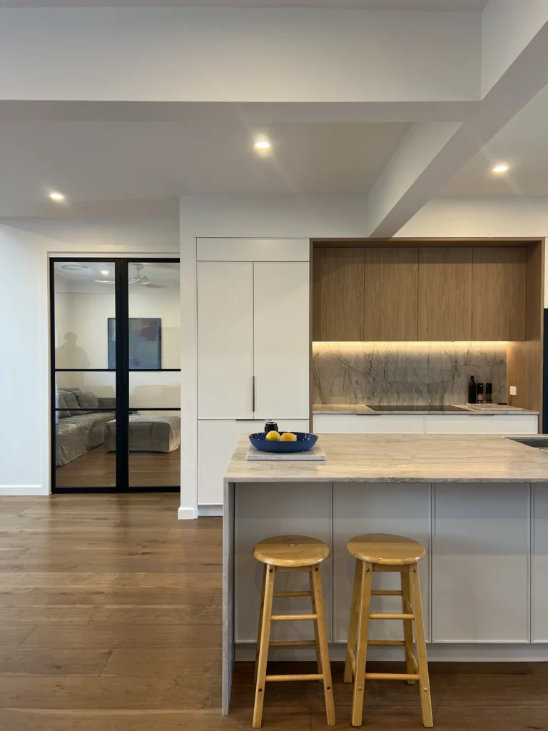 NF Build modern open plan kitchen with stone island bench, wooden bar stools, and timber flooring