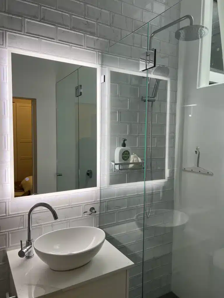 NF Build modern bathroom with backlit LED mirror, vessel sink, subway wall tiles, and glass shower screen