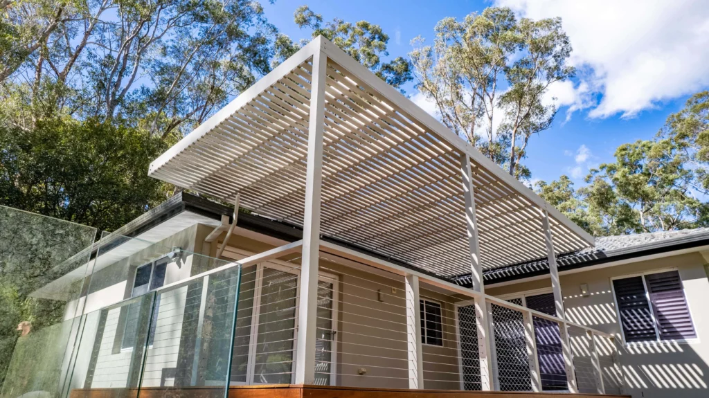 NF Build modern residential home featuring louvered pergola extension over outdoor timber deck